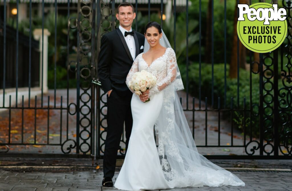 A bride and groom standing in front of a decorative wrought iron gate during their wedding.